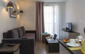 uma sala de estar com um sofá e uma mesa em Odalys City Colmar La Rose d'Argent em Colmar