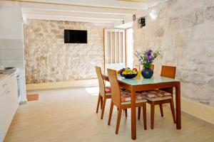 a dining room with a table and chairs and a television at Stone House Grgurevic in Rogoznica