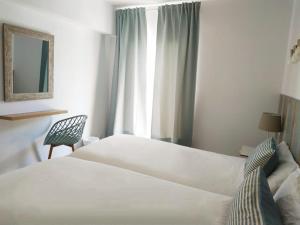 1 dormitorio con 1 cama, 1 silla y 1 ventana en Apartamentos Las Palmeras en Palmanova