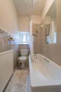 uma casa de banho com uma banheira, um WC e um lavatório. em The West End Cottage em Edimburgo