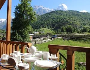 a table with white dishes on a balcony with mountains at Guest House Guli in Mestia