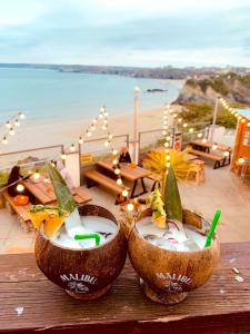two coconuts with drinks in them on a table near a beach at St Christopher's Inn Newquay in Newquay
