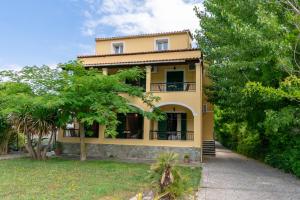 a yellow house with trees in front of it at Villa Litsa in Ermones