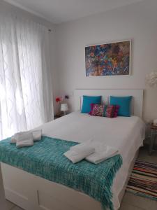 a bedroom with a large white bed with blue pillows at The Sunny Cottage in Faro