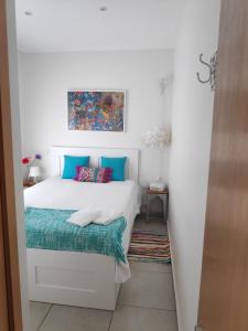 a bedroom with a white bed with blue pillows at The Sunny Cottage in Faro