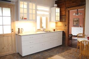 una cucina con mobili bianchi, un lavandino e un tavolo di Posti 22 külaliskorter a Haapsalu