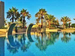 a swimming pool with palm trees in the background at Oasis Beach & Spa - Blue Pearl in Saïdia