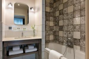 a bathroom with a sink and a tub and a mirror at Royal Madeleine Hotel & Spa in Paris