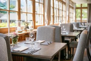 un comedor con mesas, sillas y ventanas en Seehotel Grundlsee, en Grundlsee