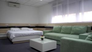 Habitación con 2 camas, sofá y mesa. en Garni Hotel Consul, en Niš