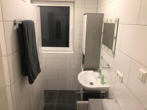 a white bathroom with a sink and a mirror at Ferienwohnung Salzgrotte in Eggolsheim