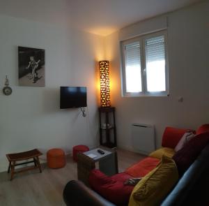 een woonkamer met een bank en een tv bij Appartement hyper-centre Epernay avec sauna et parking privé in Épernay