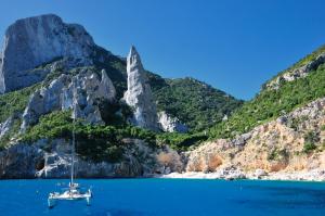 a sailboat in the water next to a mountain at Hotel Goloritzé in Baunei
