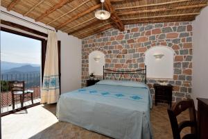 a bedroom with a bed and a stone wall at Hotel Goloritzé in Baunei