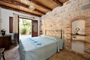 um quarto com uma cama e uma parede de tijolos em Hotel Goloritzé em Baunei