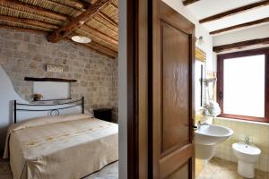 a bedroom with a bed and a bathroom with a sink at Hotel Goloritzé in Baunei