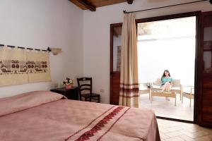 a bedroom with a bed and a woman sitting in a chair at Hotel Goloritzé in Baunei