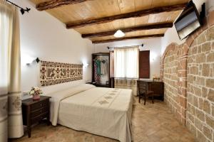 a bedroom with a bed and a brick wall at Hotel Goloritzé in Baunei