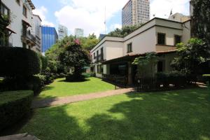 a green yard with a building in the city at Hotel Maria Cristina in Mexico City