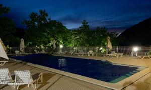 a swimming pool at night with chairs and umbrellas at LE BALCON DU GOLF in Giez
