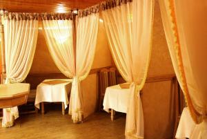 リヴィウにあるEkran Hotelのテーブル2台と白いカーテンが備わる部屋