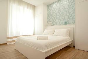 uma cama branca num quarto com uma janela em My Home-Gorgona em Livorno