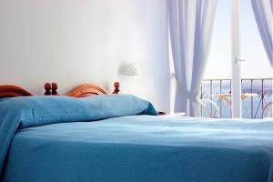 a bed with a blue blanket and a window at La Pergola del Torchio in Ischia