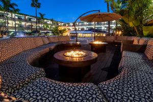 a patio with a fire pit with chairs and an umbrella at San Nicolas Hotel Casino in Ensenada