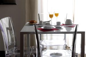 Genova46 Suites & Rooms في جينوا: طاولة مع كأسين من النبيذ وكرسيين