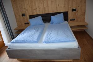 1 cama con sábanas y almohadas azules en una habitación en Haus Stefan, en Neustift im Stubaital