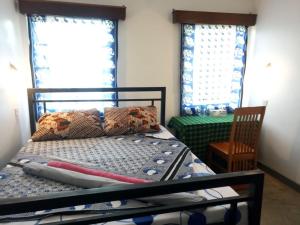 um quarto com uma cama, uma cadeira e 2 janelas em KILIMANJARO MAD MONKEY'S HOTEL em Moshi