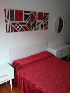 a bedroom with a red bed and a white table at Ático vacacional in Muros