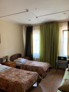 ヤロスラヴリにあるKassel Innのベッド2台と緑のカーテンが備わるホテルルームです。