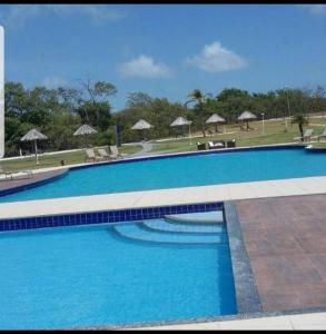 uma grande piscina azul com cadeiras e guarda-sóis em Casa Raizes Salinópolis-PA em Salinópolis