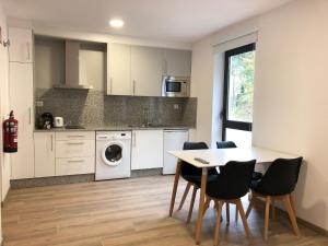 a kitchen with a table and chairs in a kitchen at Apartamentos Compostela in Lobios