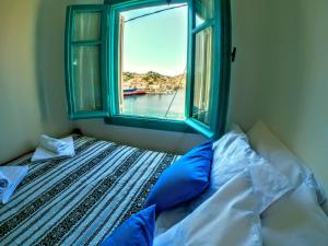 a bed with a window with a view of the water at Villa Pitini in Symi
