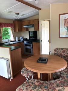 uma cozinha com uma mesa e cadeiras de madeira e uma mesa em 62 Glenfinart Caravan Park em Dunoon