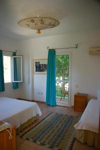 a bedroom with two beds and a window with blue curtains at Emel Pension in Güzelçamlı