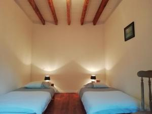 DurasにあるLes Vignes du Château Duras Wifi et Belle vueの白い壁とウッドフロアの客室で、ベッド2台が備わります。