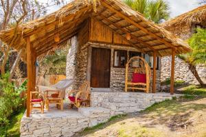 a small house with a thatched roof and chairs at Canto del Agua Ecolodge in Comitán