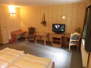 a room with two beds and a tv and a desk at Hotel Wenzels Hof in Zwethau