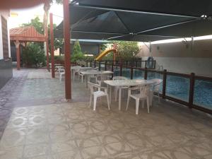 eine Terrasse mit Tischen, Stühlen und einem Sonnenschirm in der Unterkunft The Coral House in Dschidda