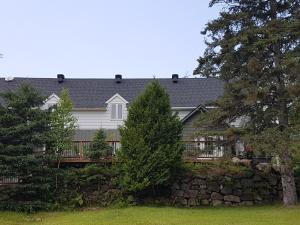una casa blanca con una valla y árboles en Hôtel Far Hills en Val-Morin
