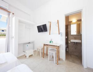 a white room with a table and a bathroom at Londos Hotel in Piso Livadi