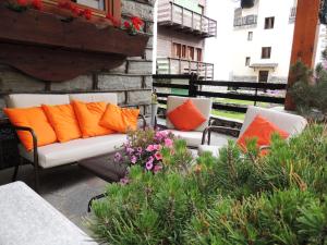 2 Stühle mit orangefarbenen Kissen auf einer Terrasse in der Unterkunft Hotel Mignon in Breuil-Cervinia