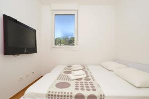 a white room with a bed and a flat screen tv at Apartment Luka in Split