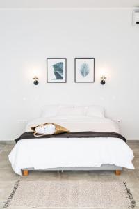 a white bedroom with a white bed with two pictures on the wall at SECRET HILL in Athani