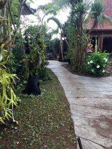 a walking path in a garden with palm trees at Kupu-kupu in Tampaksiring