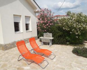 - deux chaises orange et une table sur une terrasse dans l'établissement Medjugorje Perfect family house, à Međugorje