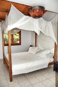 een slaapkamer met een hemelbed met witte lakens en kussens bij Villa Tara Fort Royal in Deshaies